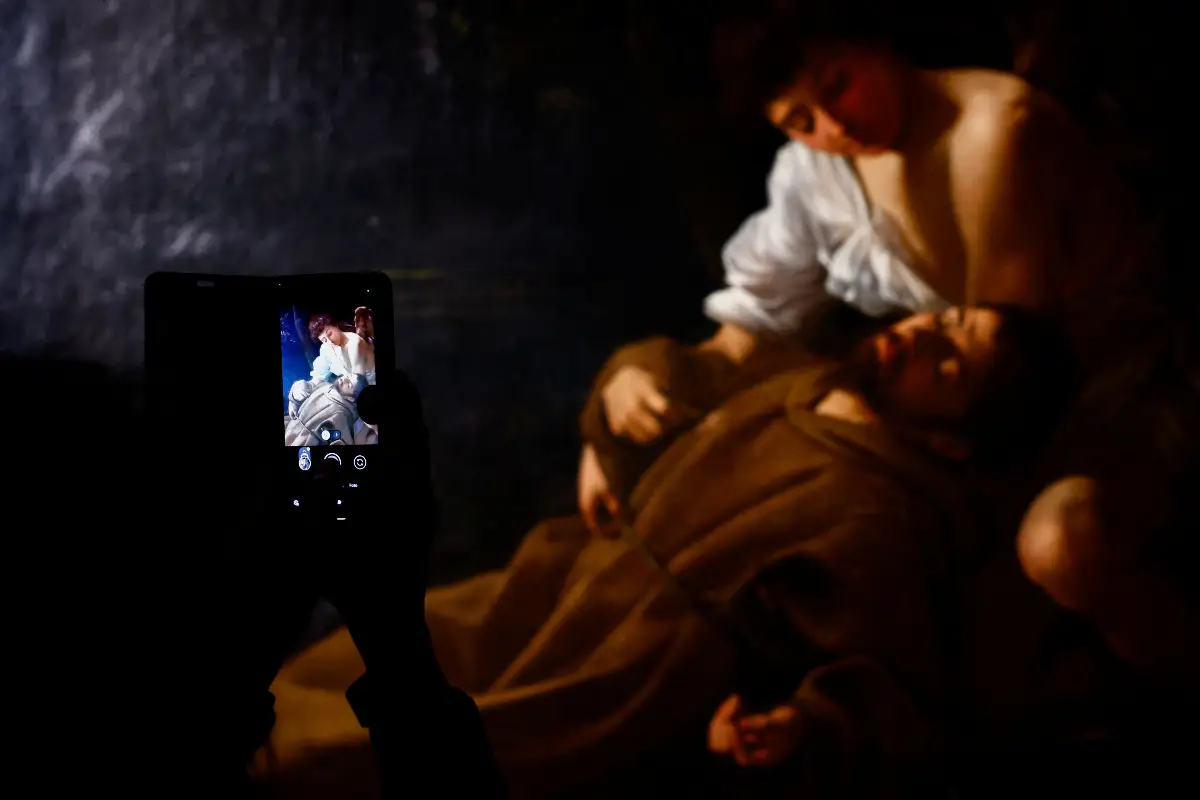 Foto de una mujer tomando foto de una obra de Caravaggio en el Palacio Barberini de Roma.