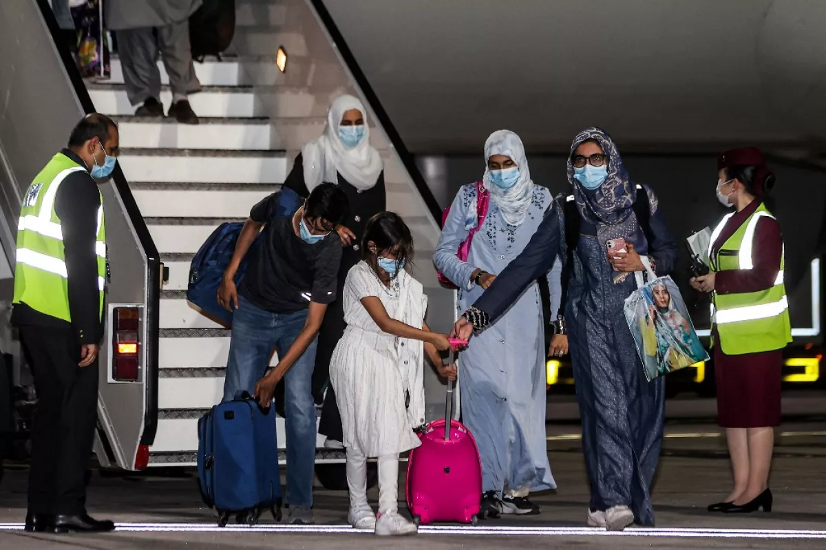 Mujeres y niñas bajan de un avión de evacuación