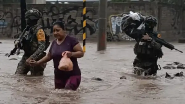 Dos integrantes del ejército ayudan a una mujer en medio de inundaciones.jpg