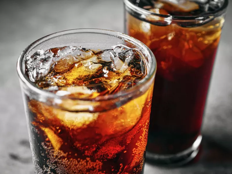 Cola soft drink with ice cubes, Close up of soda fizzy drink in Cold glass on gray background