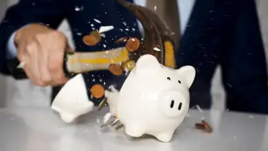 Una persona rompe una alcancía y salen disparadas unas cuantas monedas.