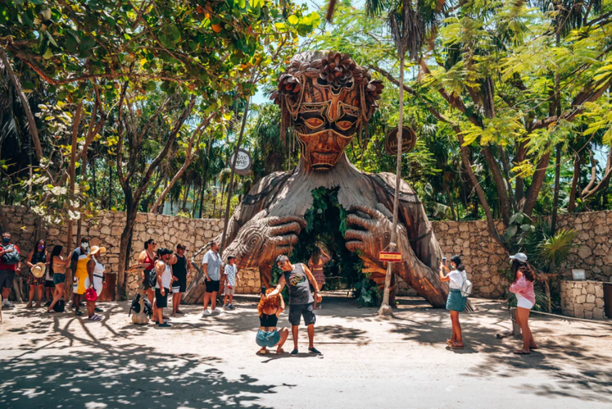 Tourists taking pictures in front of Ven a La luz sculpture at resort Ahau