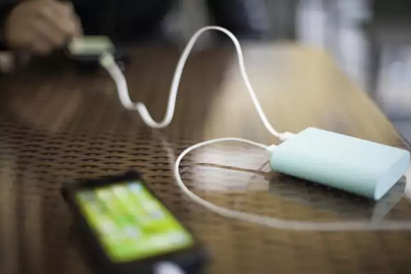 Portable external battery charging two smartphones in use