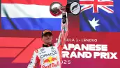 Foto de Max Verstappen con la bandera de Países Bajos detrás y alzando el trofeo del Gran Premio de Japón.