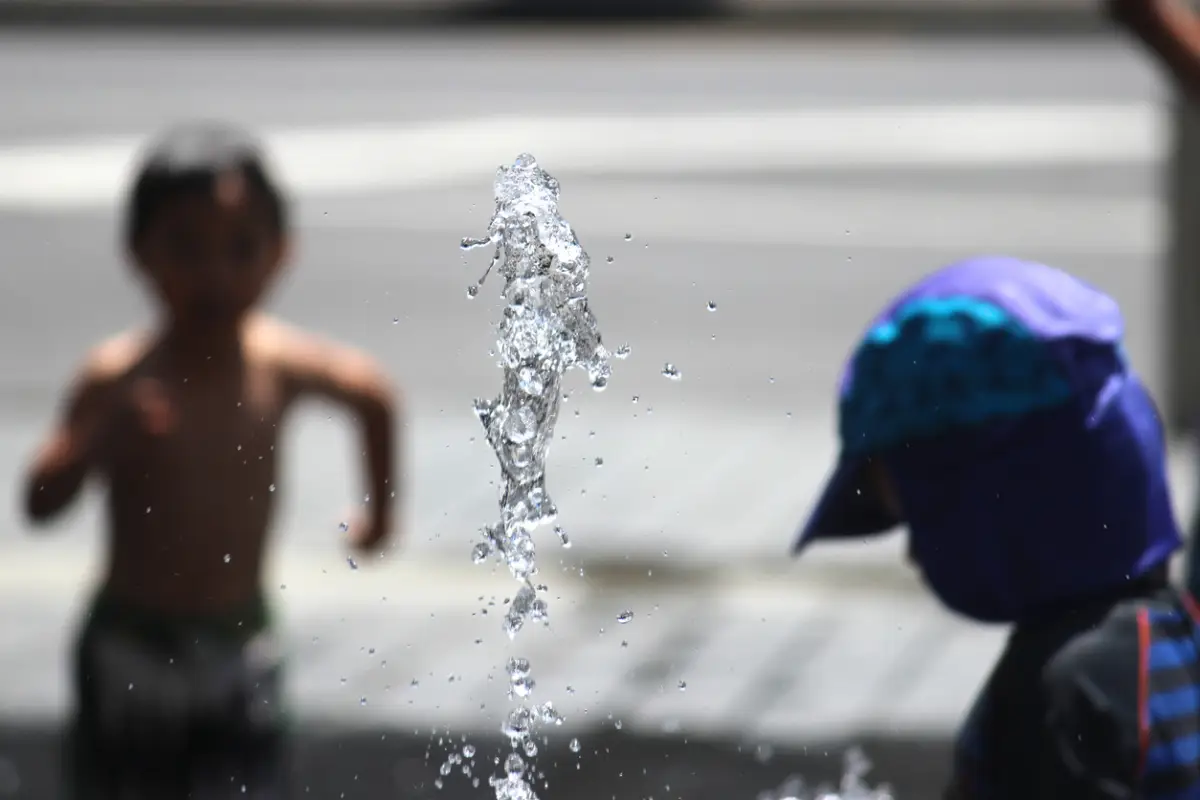 Dos niños juegan en una fuente. 