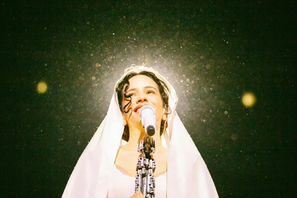 Retrato de Rosalía durante su concierto Lux Tour. En la imagen se ve a la cantante barcelonesa con un Manto blanco en la cabeza mientras interpreta el tema "Mio Cristo Piange Diamanti". 