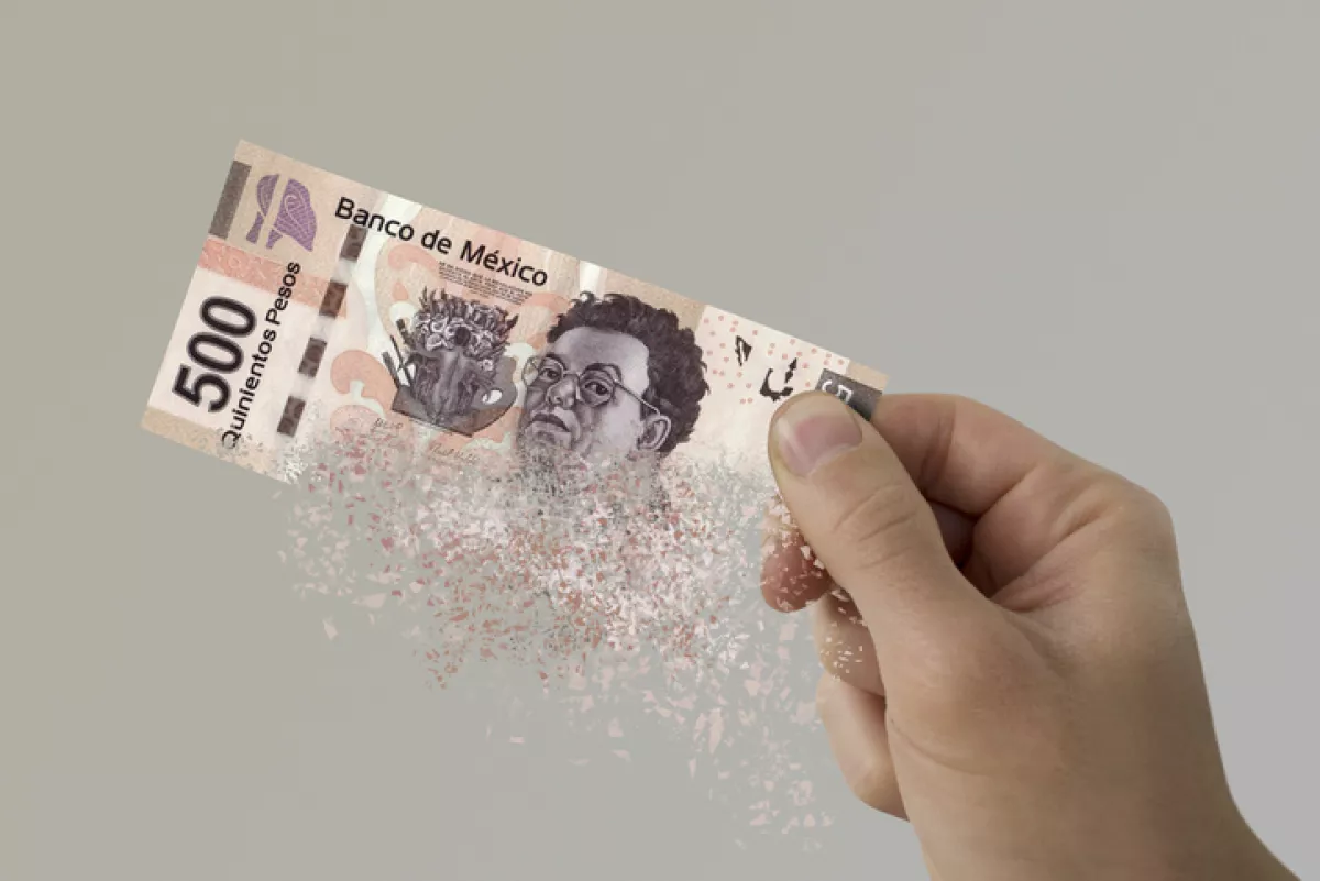 Mexican Pesos bill pulverizes in a man's hand.