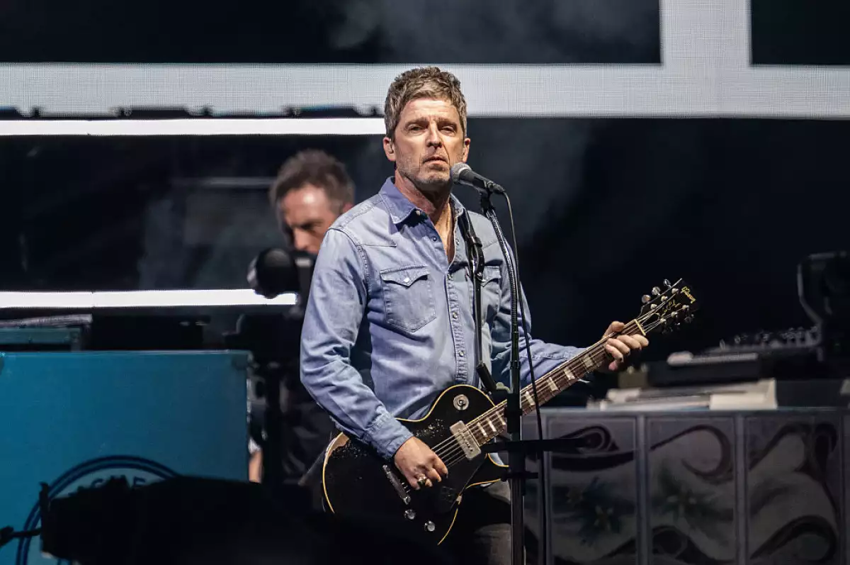 Foto de Noel Gallagher tocando la guitarra durante el primer concierto de Oasis en Cardiff.