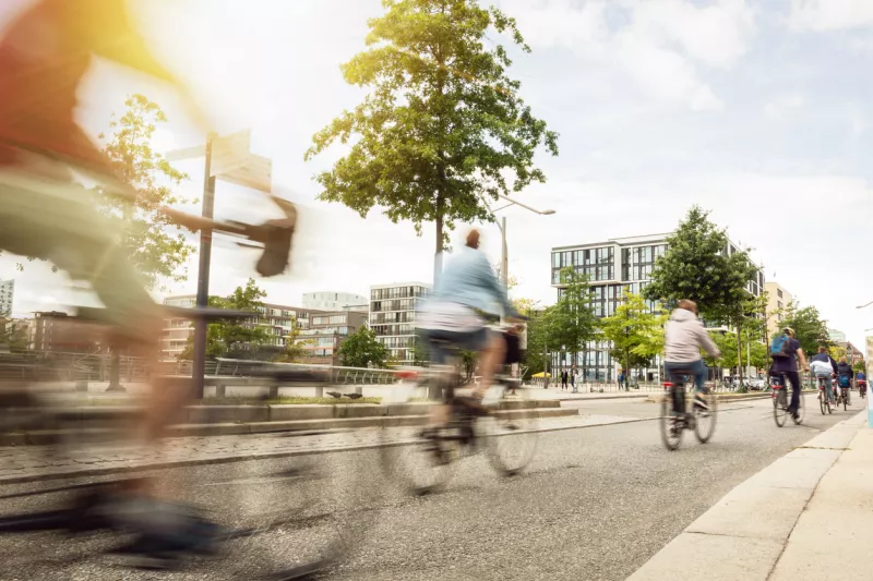 Foto de larga exposición de ciclistas recorriendo una calle con árboles alrededor