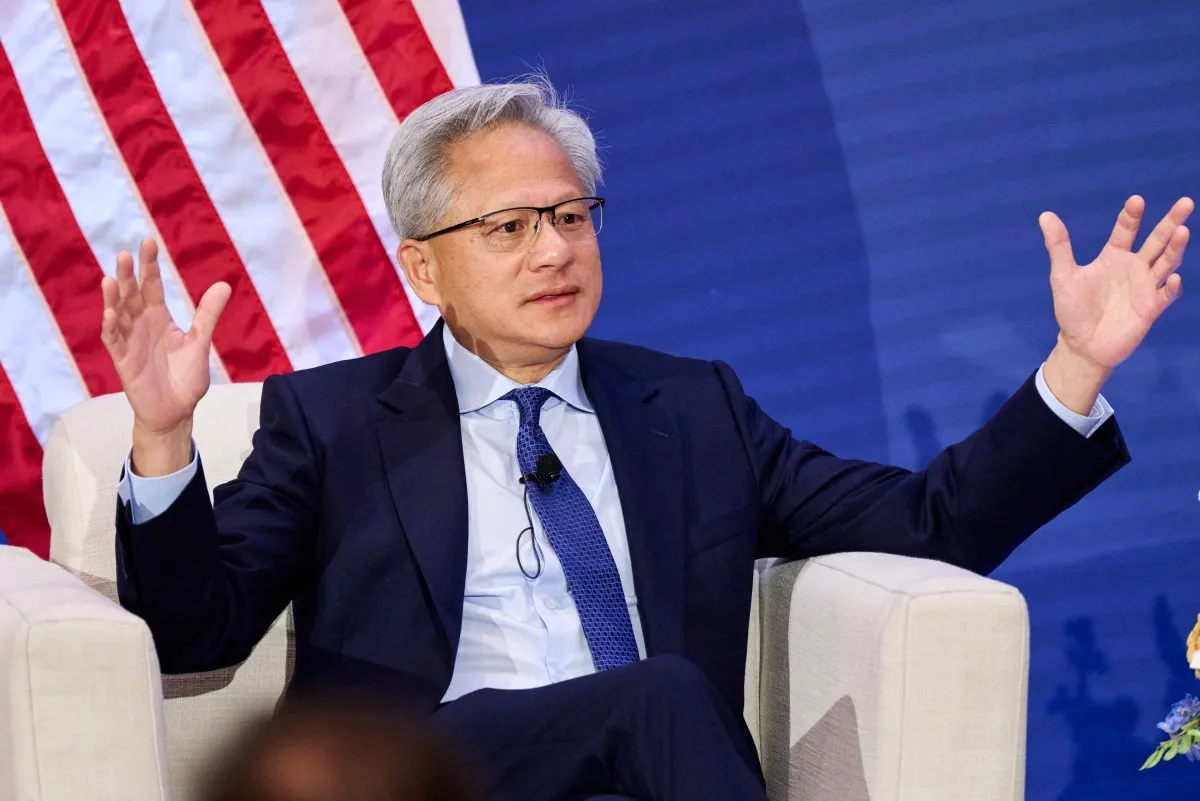 Jensen Huang sentado con los brazos abiertos durante una conferencia. 
