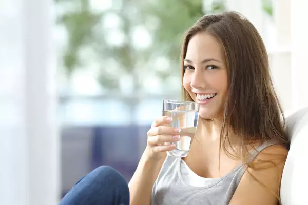 Girl,Drinking,Water,Sitting,On,A,Couch,At,Home,And