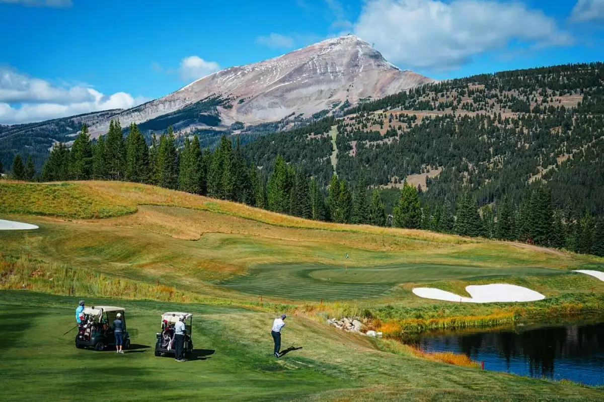 Foto del club de golf del Yellowstone Club en Montana con las montañas nevadas de frente.