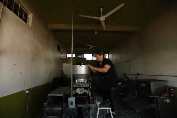 Una mujer revisa una máquina en el interior de una tortillería