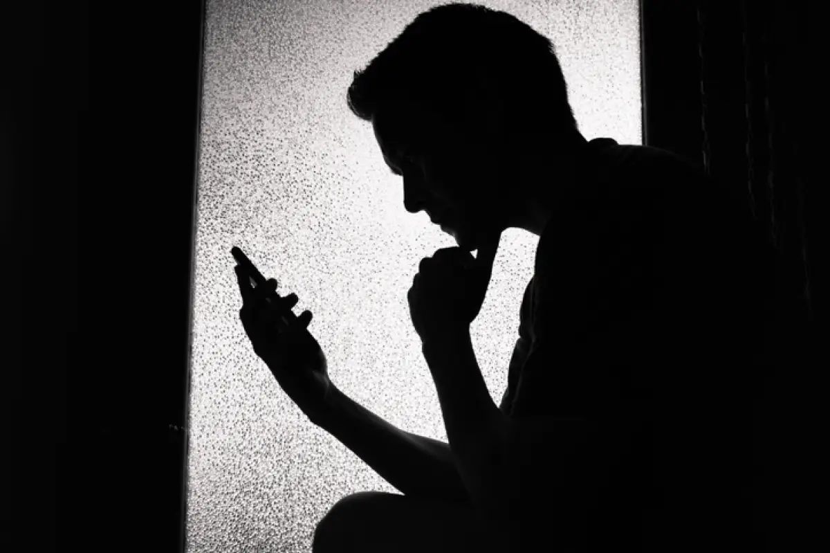 Young man reading on smartphone at home.