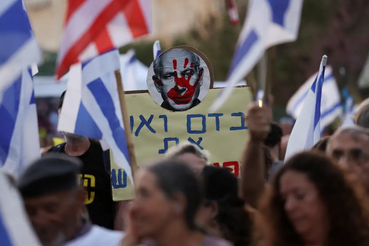 Un manifestante sostiene un cartel con una imagen del rostro del primer ministro israelí, Benjamín Netanyahu, con una huella de una mano roja, mientras la gente exige el derrocamiento de Netanyahu, tras el mortal ataque del 7 de octubre contra Israel por parte del grupo islamista palestino Hamas y la guerra subsiguiente. en Gaza, en una manifestación en Jerusalén, el 1 de abril de 2024.