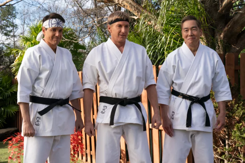 Foto de Ralph Macchio y William Zabka en uniformes de karate con cinta negra.