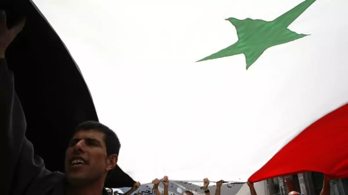manifestantes sostienen una bandera de siria