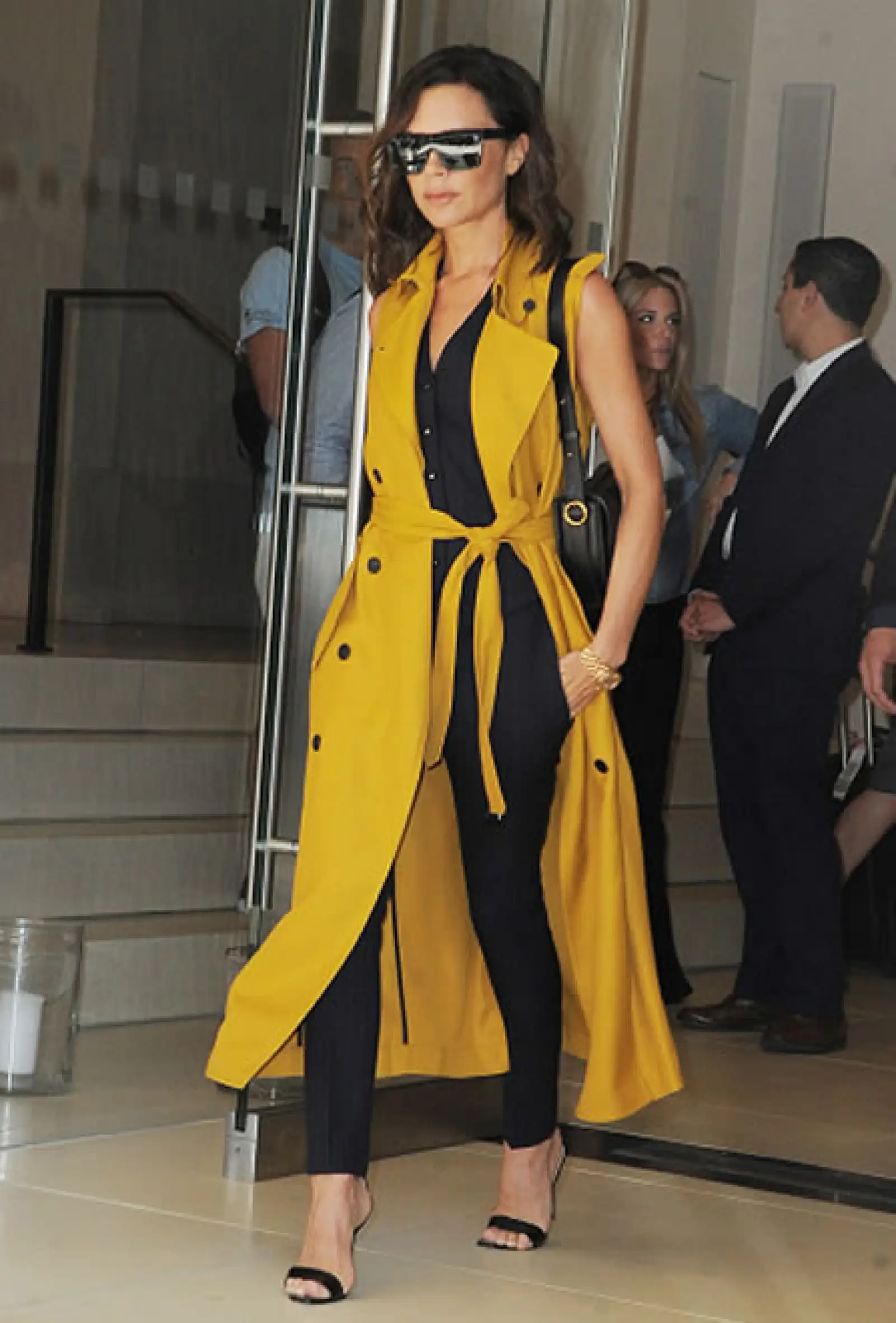 Posh spice avivó su look con una cabardina sin mangas color mostaza de la colección pre-spring 2017 de su firma homónima.