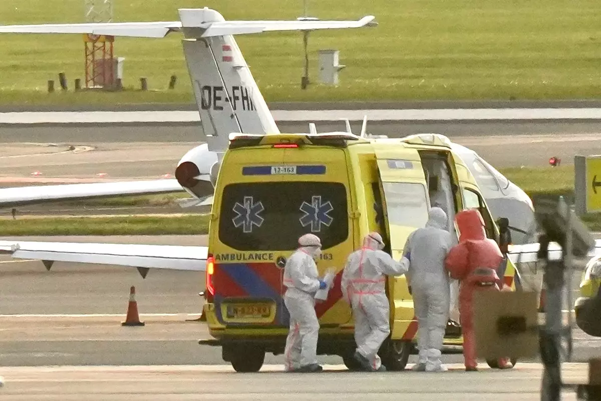 Una ambulancia que transporta a una persona contagiada por hantavirus en un crucero, alrededor hay médicos con trajes especiales de protección. 