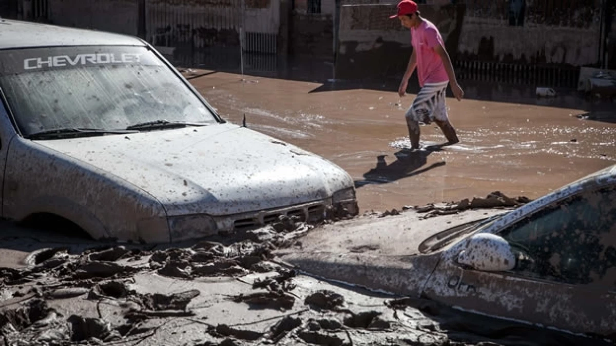Un afectado por las inundaciones al norte de Chile camina por una calle llena de lodo