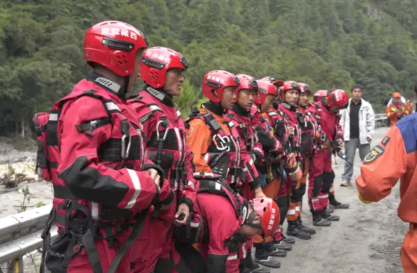 Personal de bomberos y equipos de rescate se reúnen antes de llevar a cabo operaciones de rescate en un tramo de la carretera que conduce al puerto de Gyirong, dañado por un deslizamiento de tierra dos días antes.