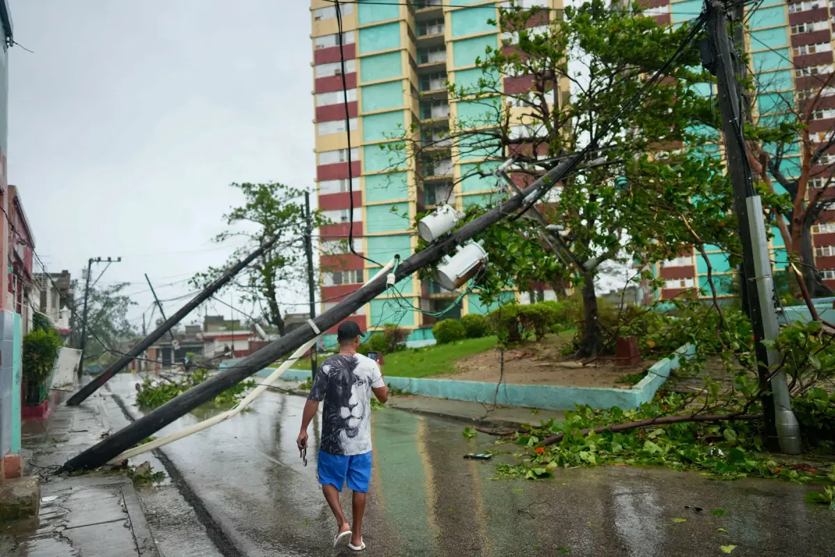 Un hombre toma fotos de postes eléctricos caídos en la calle después del huracán Melissa en Santiago, Cuba, el 29 de octubre de 2025.