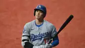 foto de shohei ohtani, jugador estrella de los angeles dodgers, carga un bat entre sus manos.