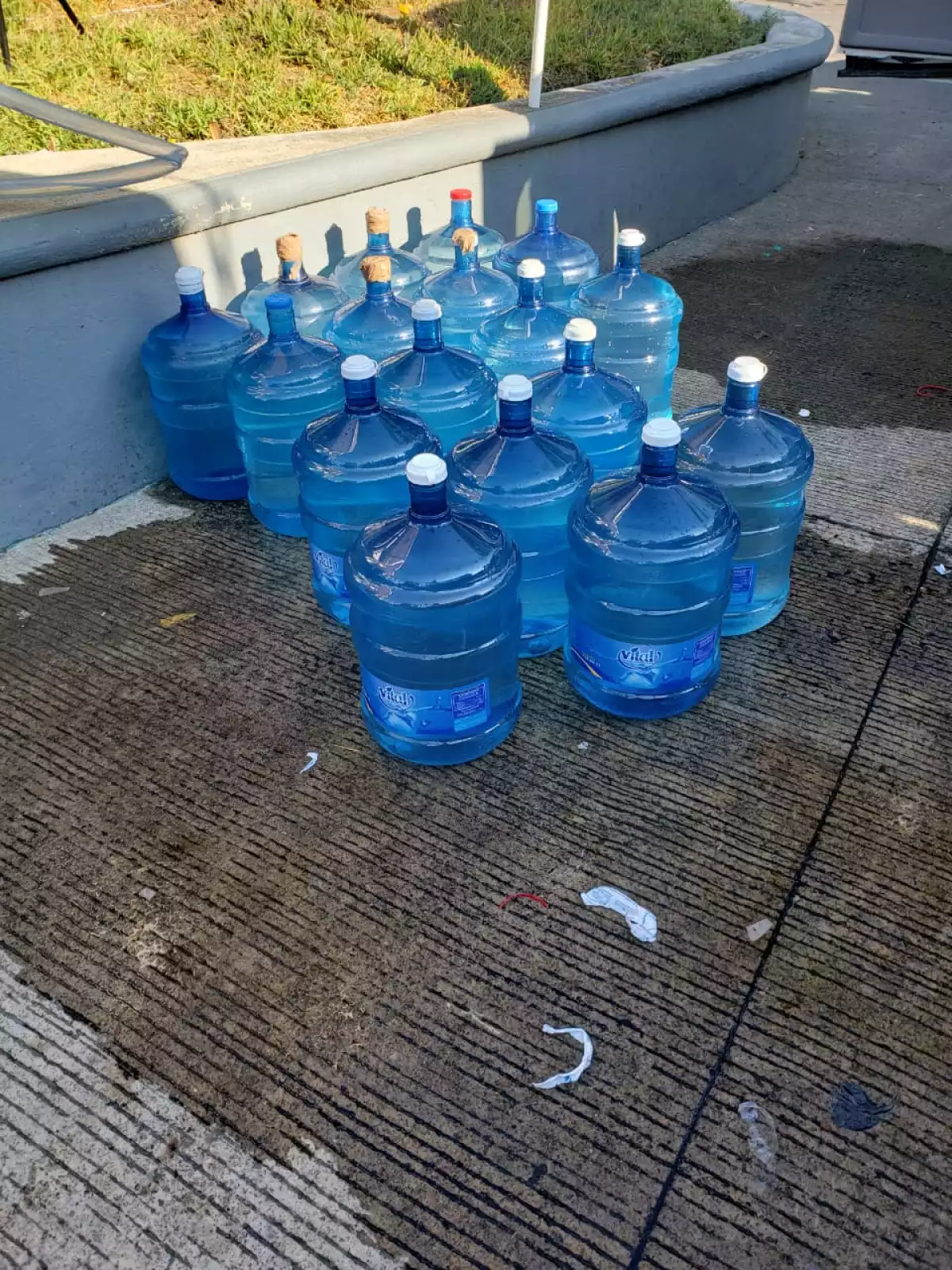 Garrafones que se llenan con manguera en estación migratoria.