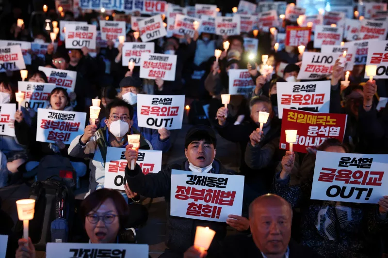 Los surcoreanos cantan eslóganes durante una vigilia a la luz de las velas que denuncia un plan del gobierno para resolver una disputa sobre la compensación a las personas obligadas a trabajar bajo la ocupación japonesa de Corea de 1910-1945, en Seúl, Corea del Sur, el 6 de marzo de 2023. 