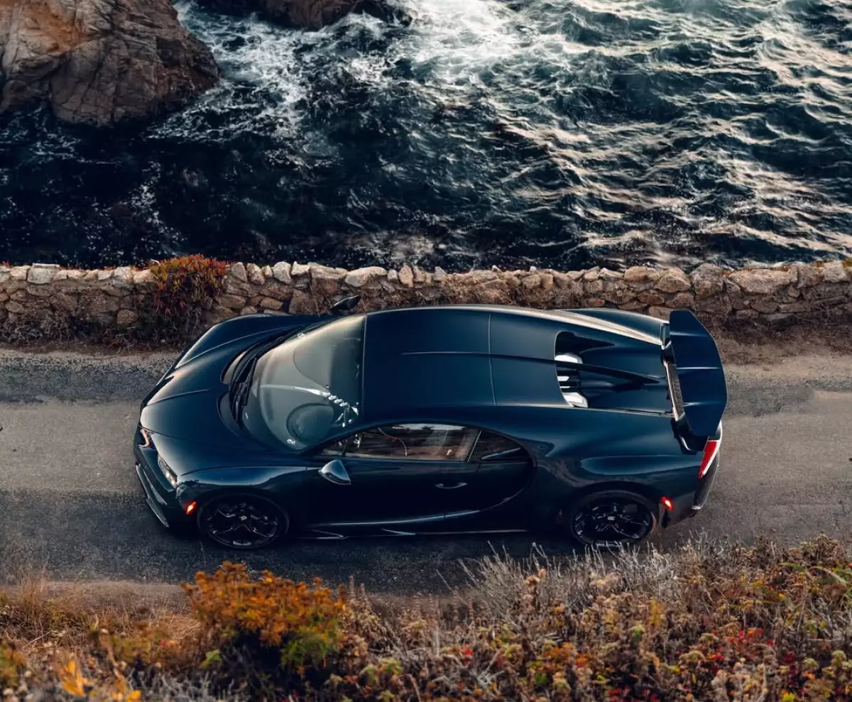 Foto de un auto Bugatti Chiron negro frente al mar.