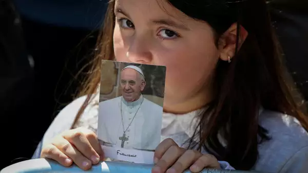 Una niña sostiene una foto del difunto Papa Francisco mientras espera la llegada de su ataúd fuera de la Basílica Papal de Santa María la Mayor, el día de su funeral, en Roma, Italia, el 26 de abril de 2025.
