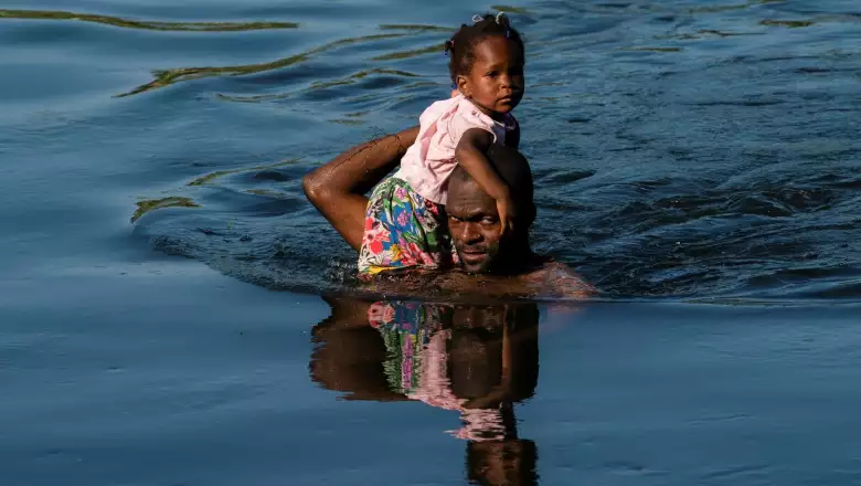 Asylum-seeking migrants wait to be processed under the International Bridge in Texas