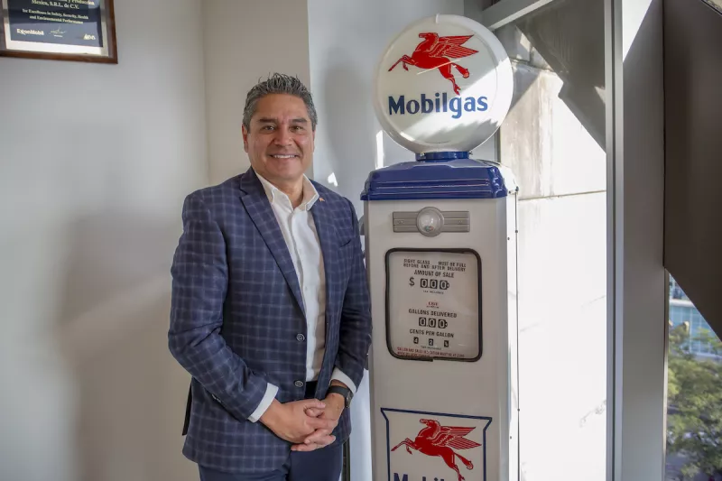 Foto de Alejandro García, director de Marketing para el negocio de combustibles de ExxonMobil en México, posando ante una replica de una bomba despachadora de gasolina antigua con logos de la marca.