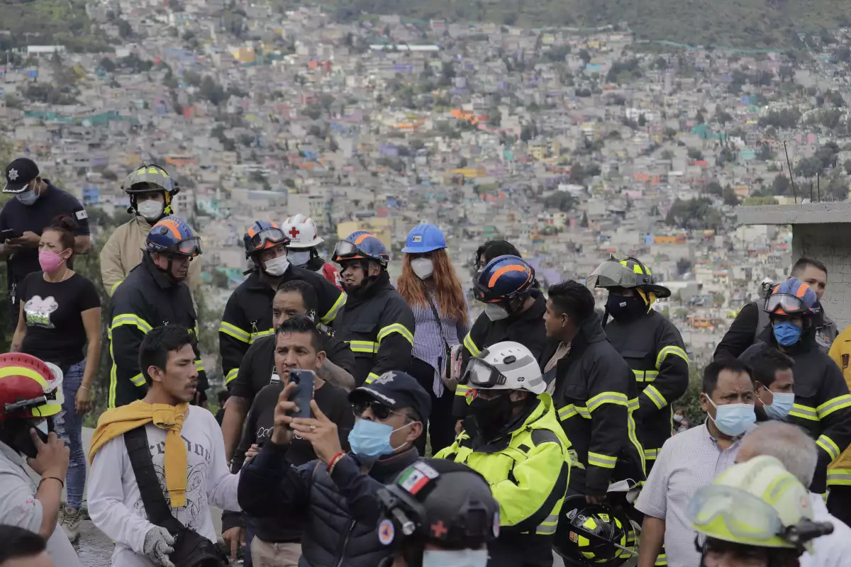 Rescatistas y autoridades mirando el desgaje del Cerro del Chiquihuite con la mancha urbana de Tlalnepantla al fondo. 
