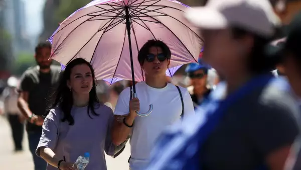 Personas en la calle se protegen con una sombrilla de la tercera ola de calor en México