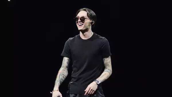 Foto de Peso Pluma vestido de negro con el micrófono en la mano durante un concierto en cdmx