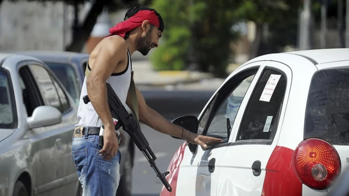 un rebelde libio conversa con un automovilista en un punto de control