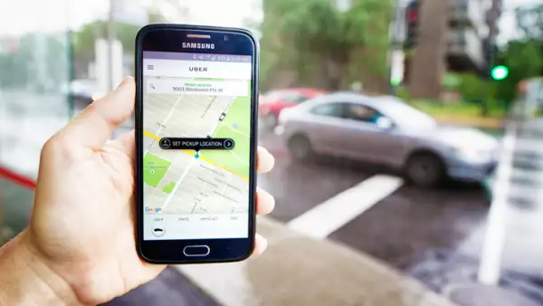 Personal perspective view of hand holding phone ordering Uber ride