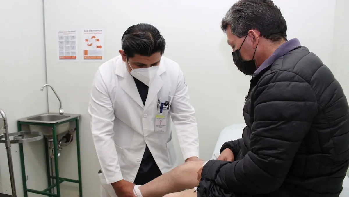 Un médico que viste bata blanca revisa la pierna de un paciente. 