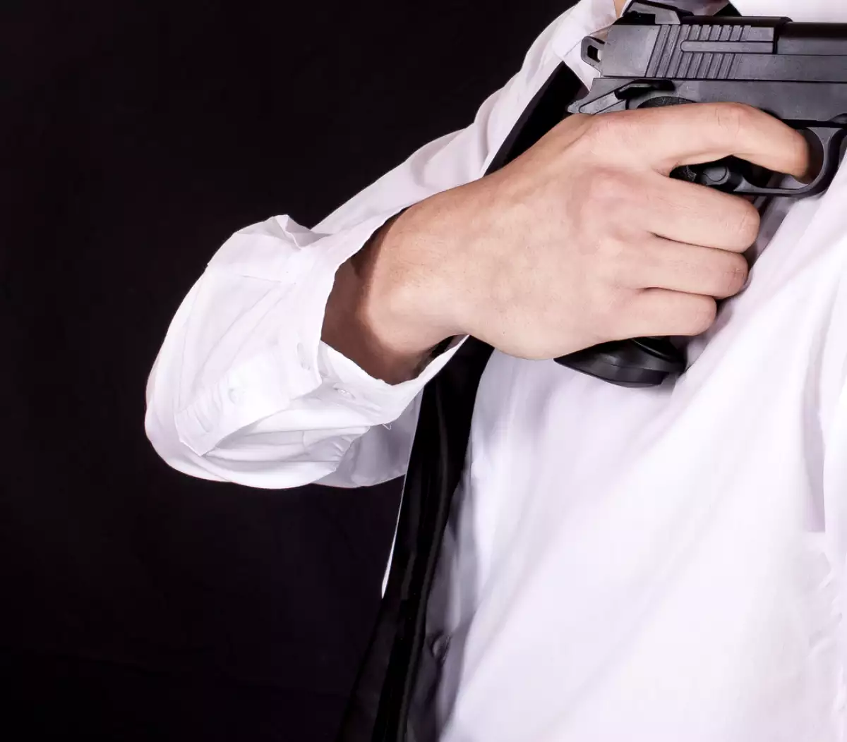 Man in black suit holding gun in hand. Secret agent, mafia, bodyguard concept.