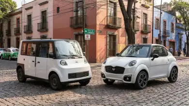 Olinia Uno y Zacua MX3 estacionados frente a frente en una calle de la Ciudad de México, rodeados de edificios y vehículos urbanos.