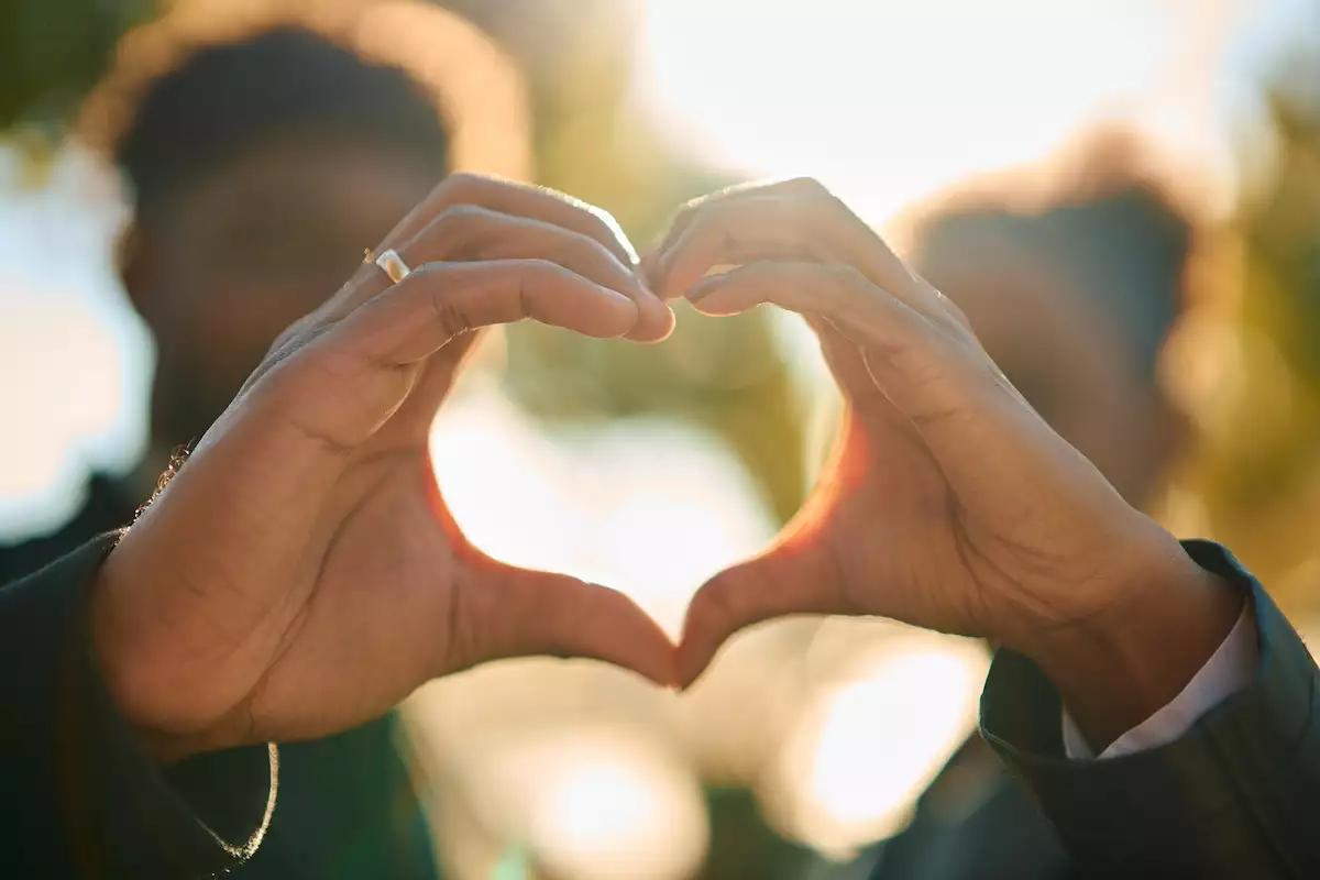 Couple forming heart shape with hands against sunlight