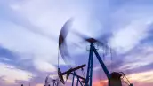 Sitio del campo petrolero, por la noche, las bombas de aceite están funcionando, la bomba de aceite y la hermosa puesta de sol reflejadas en el agua, la silueta de la unidad de bombeo de vigas por la noche.
