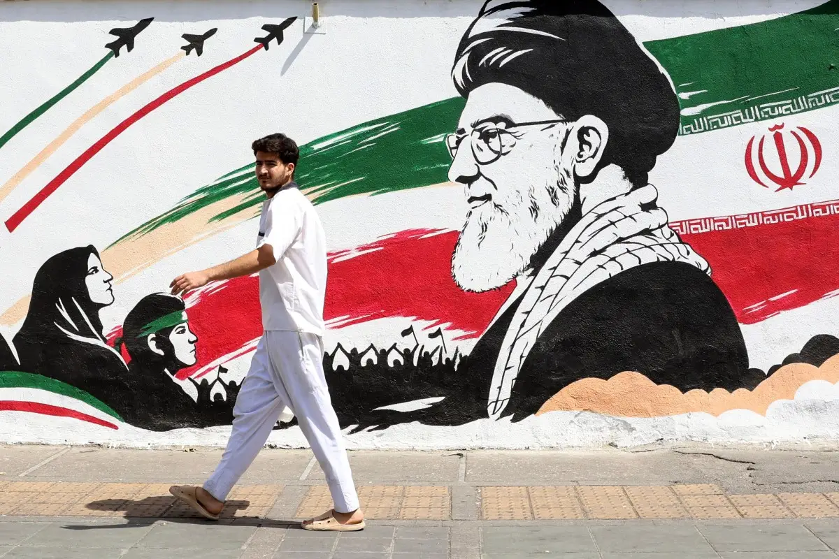 Un hombre pasa junto a un mural que representa al difunto líder supremo iraní Ayatolá Ali Khamenei en Teherán el 24 de julio de 2026. El ejército de Irán dijo el 24 de julio que llevó a cabo ataques con drones contra varias instalaciones y bases militares estadounidenses en Bahréin y Jordania en represalia por los últimos ataques estadounidenses contra la República Islámica.