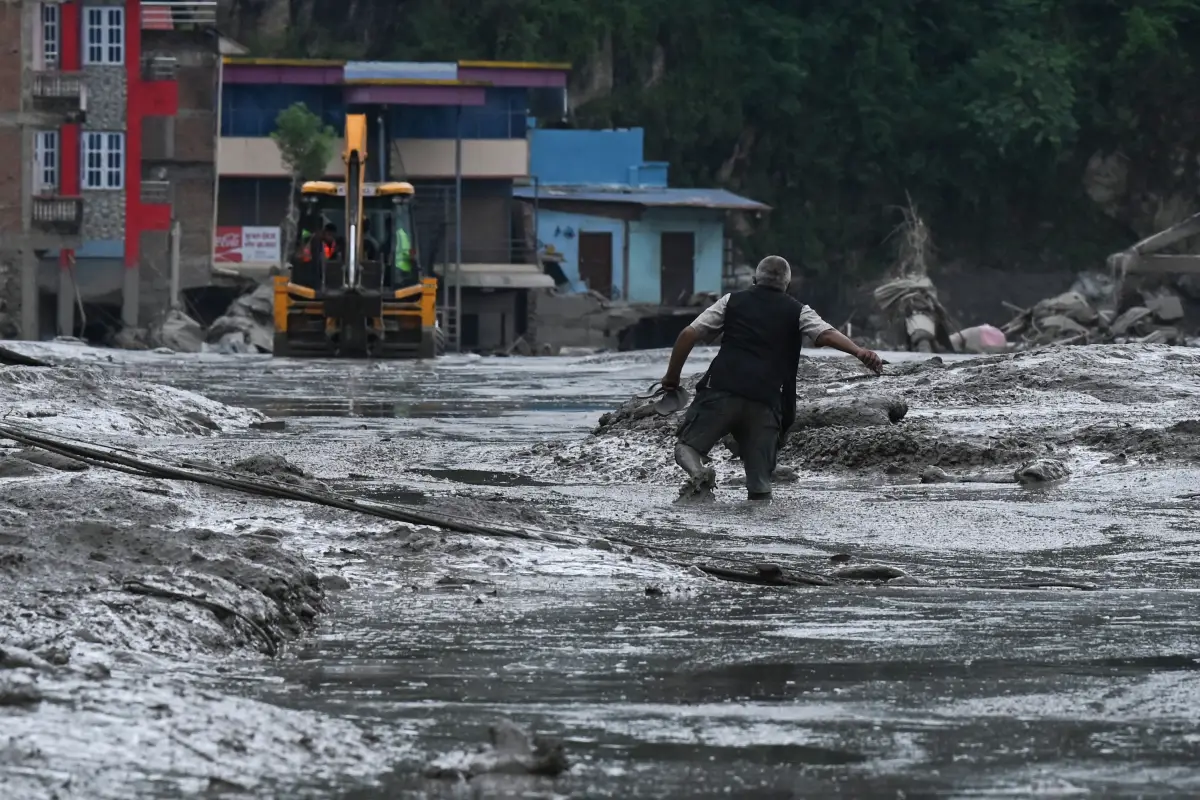 Un residente camina por una calle cubierta de barro tras unas inundaciones repentinas y un deslizamiento de tierra en Devighat, en el distrito nepalí de Nuwakot, el 26 de agosto de 2026. Los equipos de rescate se movilizaron con urgencia el 27 de agosto para localizar a cientos de personas desaparecidas en la frontera entre Nepal y el Tíbet, a causa de inundaciones repentinas y deslizamientos de tierra que causaron la muerte de al menos 160 personas y arrasaron aldeas enteras. 
