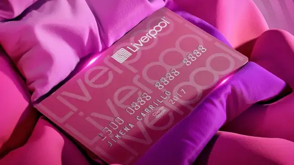 Tarjeta de crédito color rosa con los 16 dígitos del número del plástico y el nombre de Jimena Carrillo y una fecha de vencimiento. El plástico color rosa tiene la leyenda liverpool tres veces y el logo de la cadena en color blanco en la parte superior izquierda.