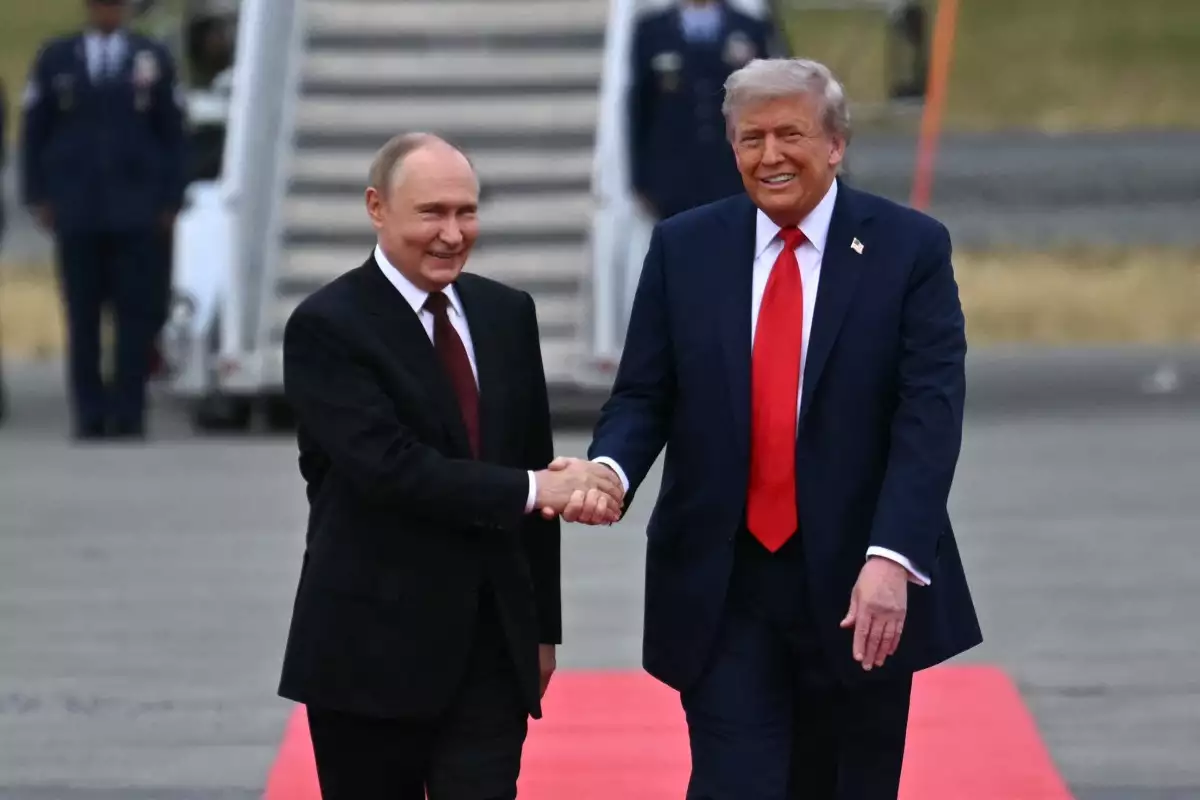 El presidente estadounidense Donald Trump (R) estrecha la mano y saluda al presidente ruso Vladimir Putin en la pista después de que llegaran a la Base Conjunta Elmendorf-Richardson en Anchorage, Alaska, el 15 de agosto de 2025.