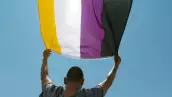person waving a non-binary pride flag