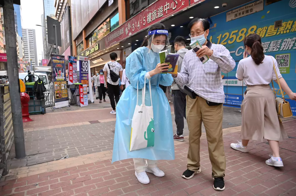 Una mujer con equipo de protección personal promueve los kits de prueba de COVID-19 en Hong Kong.