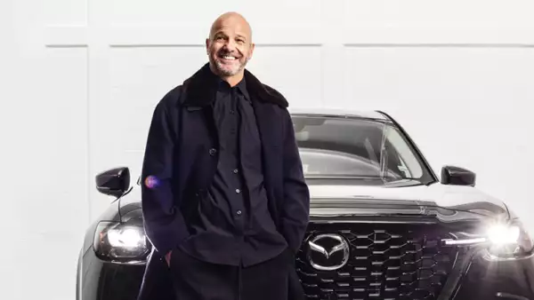 Foto de Luis García vestido de negro recargado en una suv de mazda